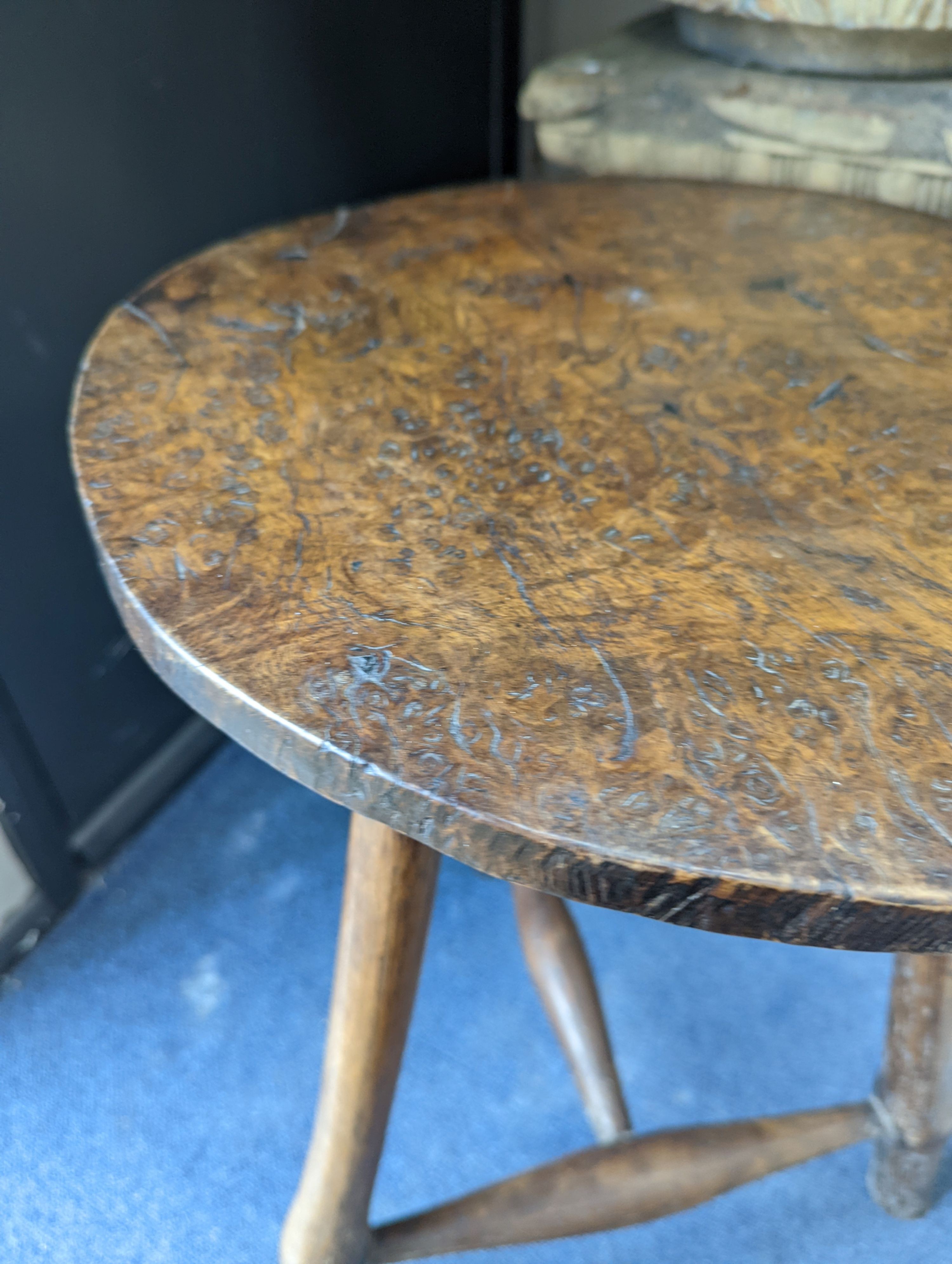 A circular burr elm and ash primitive cricket table with T shaped stretcher, diameter 44cm, height 61cm